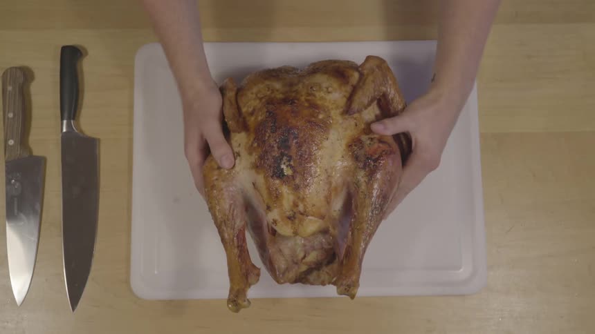 A person places a cooked turkey on a cutting board