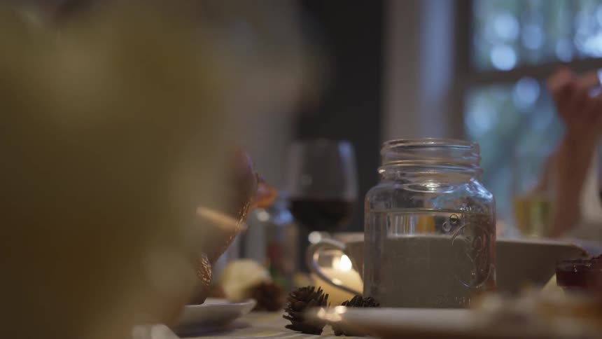 Hand reaches for glass of red wine on dinner table