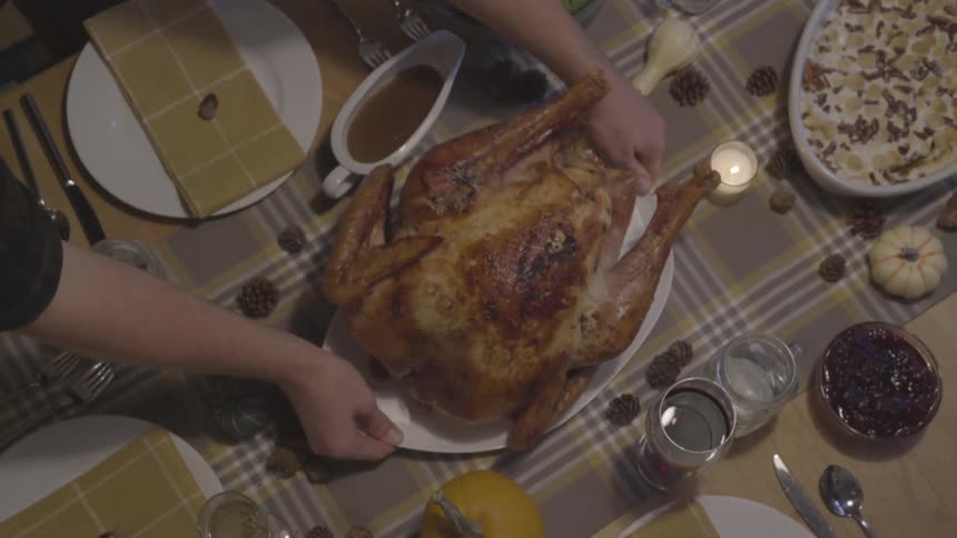 Person places turkey in center of set dining table