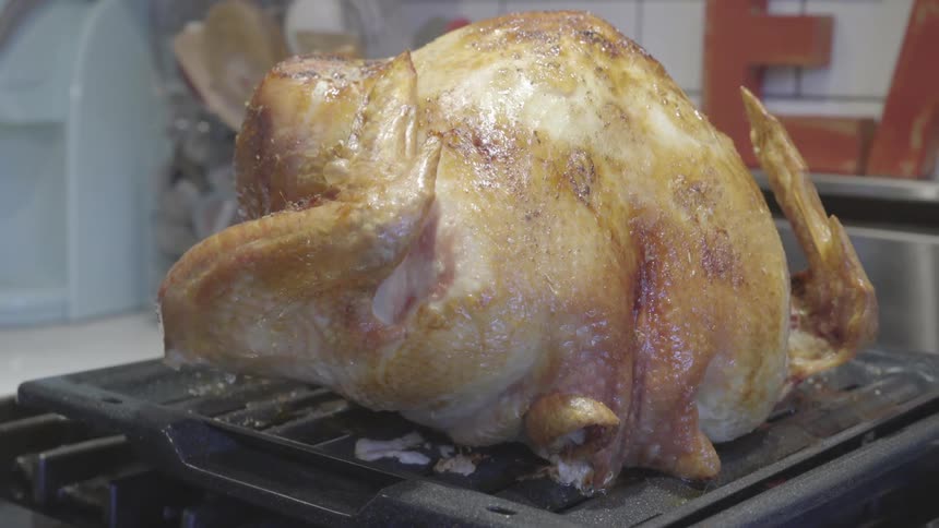 A cooked whole chicken atop an oven