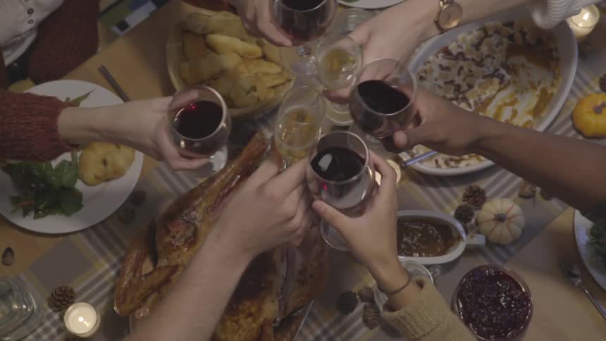 A group of people toast over a dinner table covered in a food