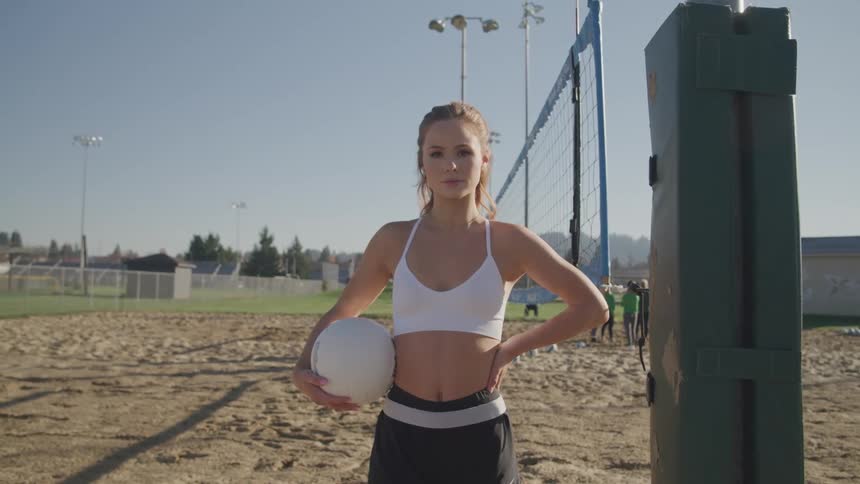 Woman stands near volley ball court near other sports fields