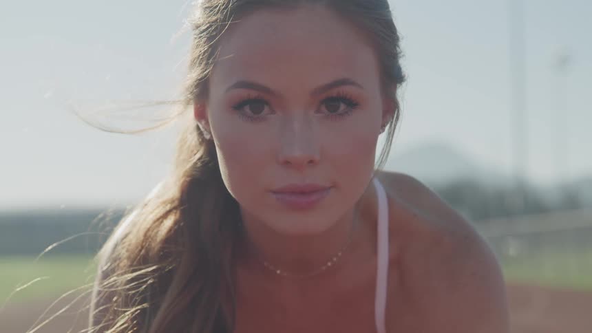 Young blonde woman set to compete in a race track looks at the camera
