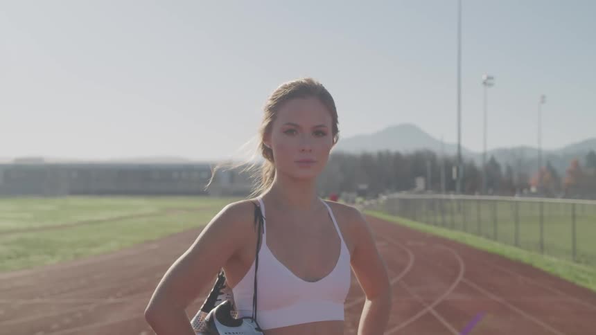 A woman stands on the track and field by herself