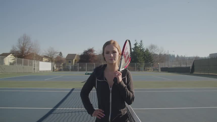 A woman stands on a tennis court holding a racket