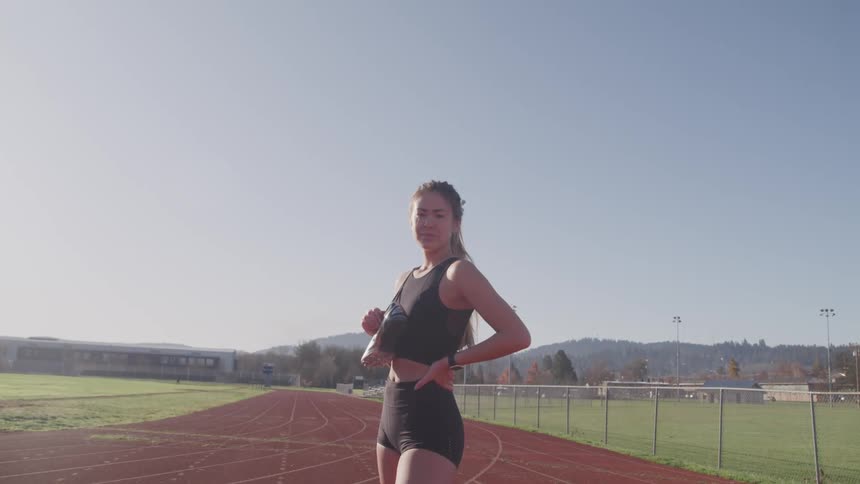 A female standing on a track wearing work out clothing
