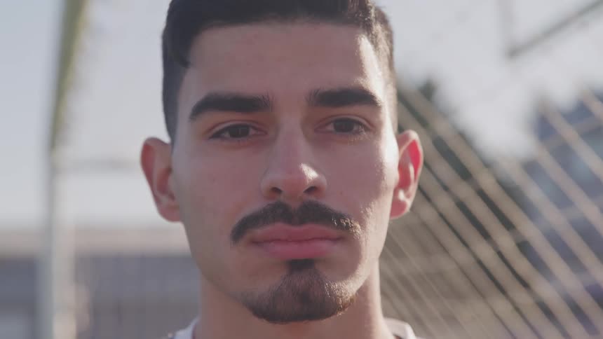 Man with mustache and beard stands near soccer goal