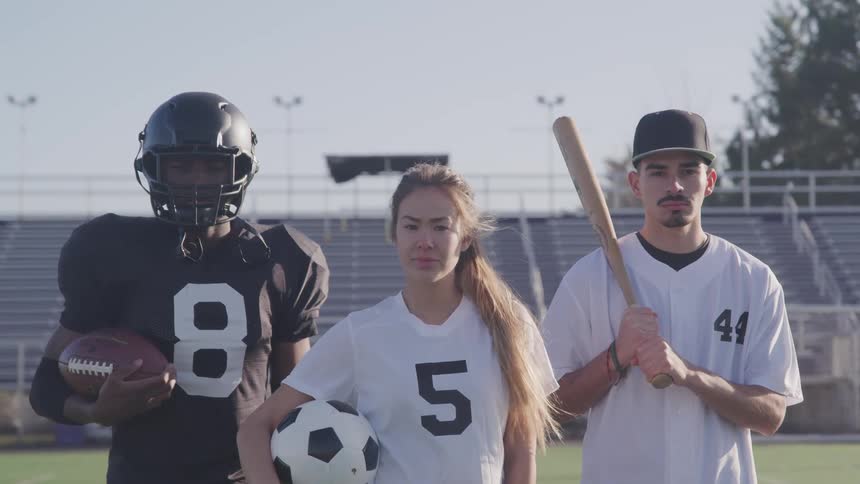 Three teenage athletes standing in a stadium posing for a photo