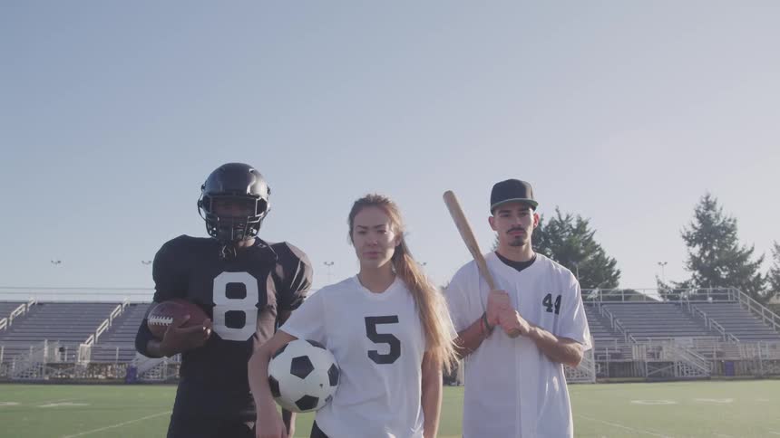 Football player soccer player and baseball player standing together on field