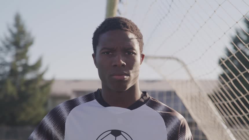 Young man in soccer jersey stands in soccer goal