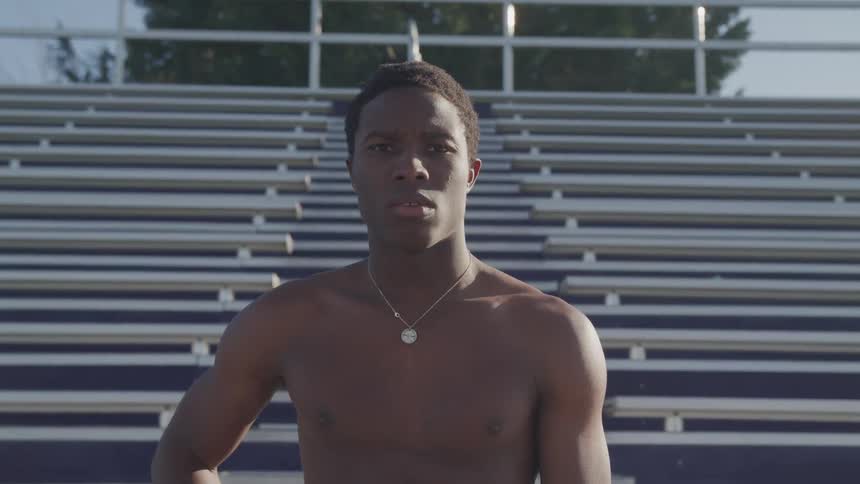 A teenage boys standing at the bottom of set of bleachers at a stadium