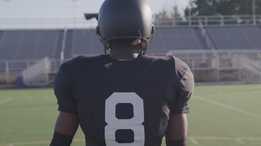 A man with a football jersey and helmet standing on a football field