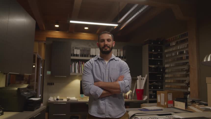 A man in a collared shirt is standing near a lamp