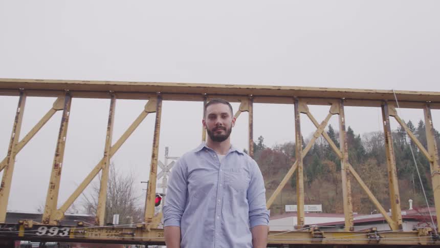 Man stands near flashing railway crossing as train passes behind him