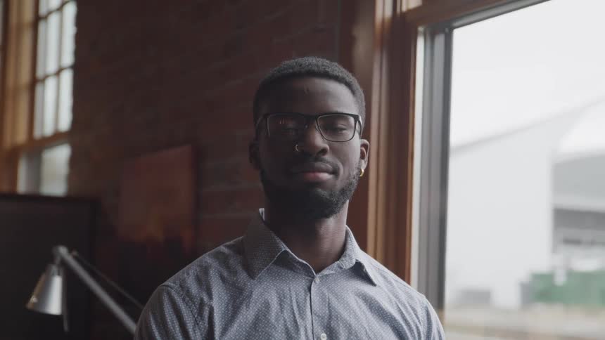 A young black man stands in a building and looks ahead