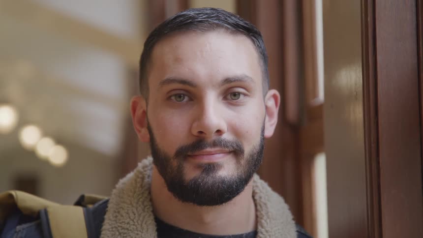 Young man with beard smiles at camera