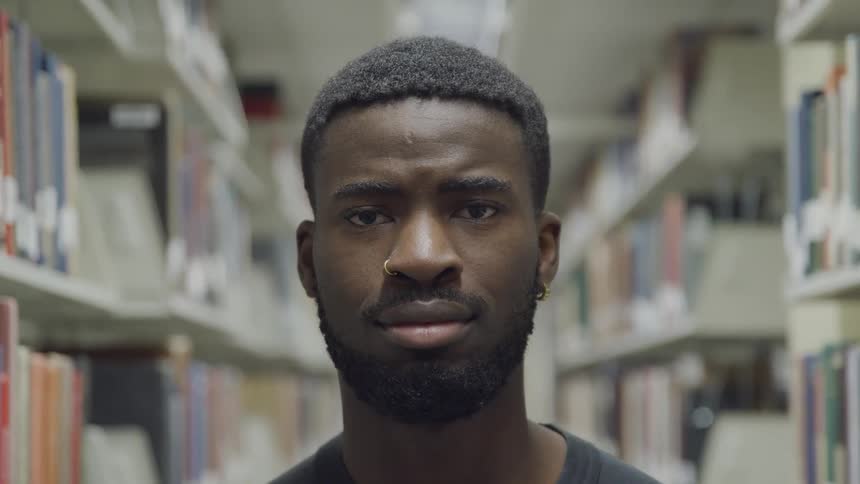 A man standing in between shelves of books in a library