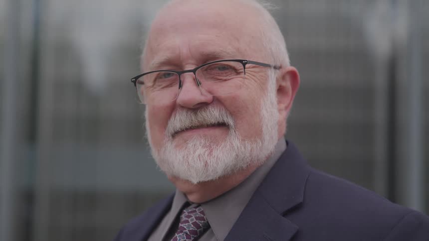 A man is standing outdoors while wearing a suit