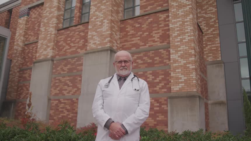 A doctor is standing outdoors by a building