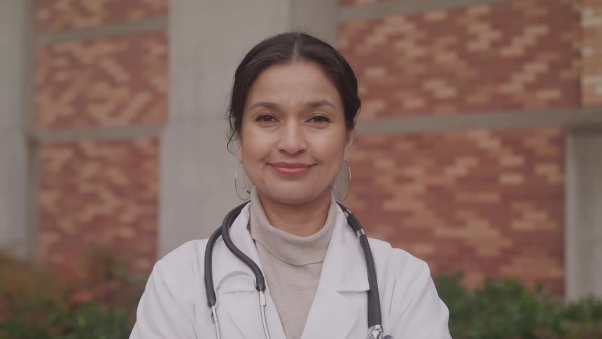 Woman in lab coat with stethoscope smiles