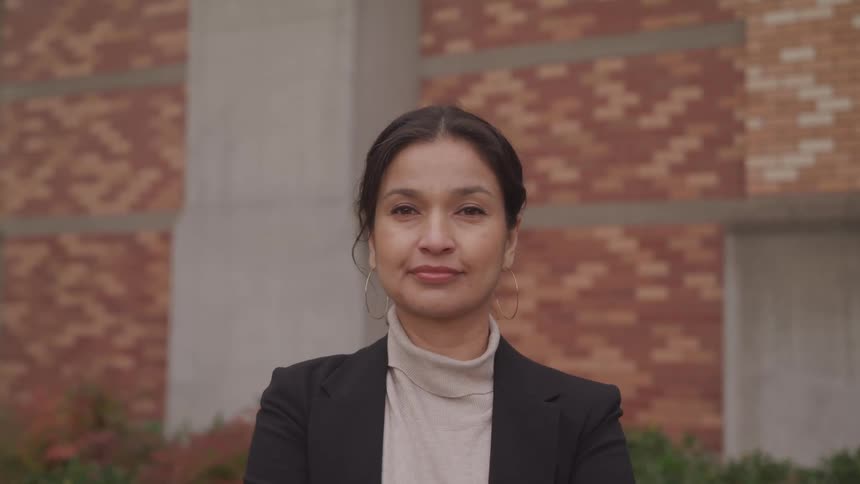 Woman standing in front of brick wall turns to camera