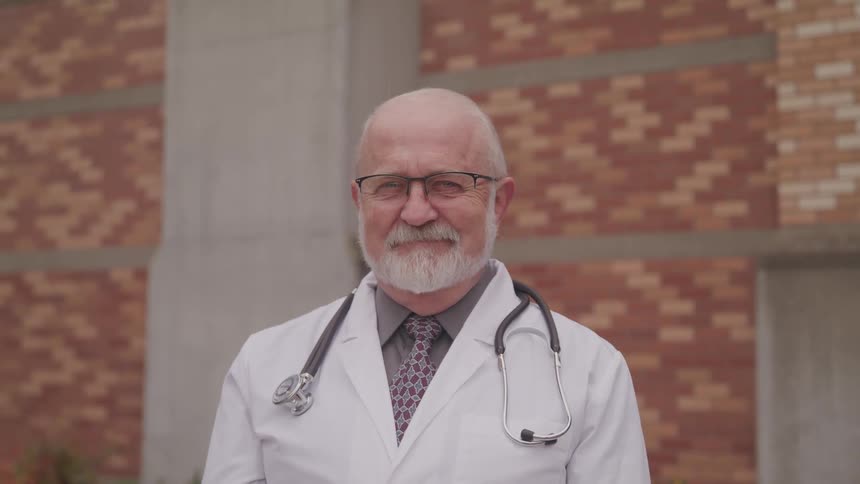 A doctor standing outside a building smiling