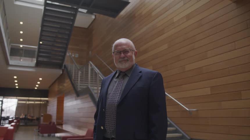 Senior citizen wearing a suit standing in the lobby of a building looking at the camera
