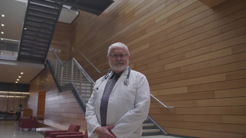 A doctor is standing inside of a building and smiling