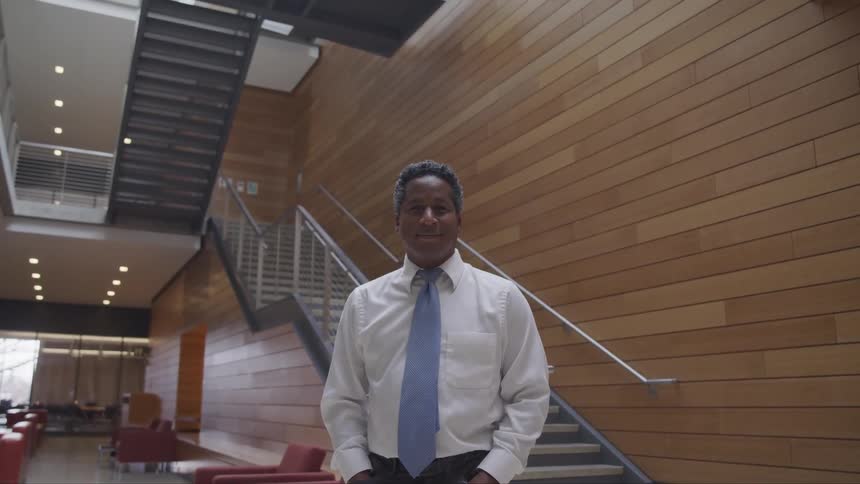 Man stands near staircase in office building in casual business a tire