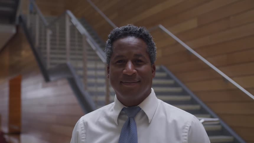 A man is smiling and standing inside a building