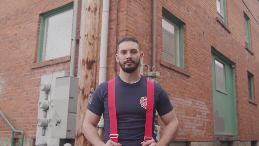 A firefighter stands outside of a large brick building