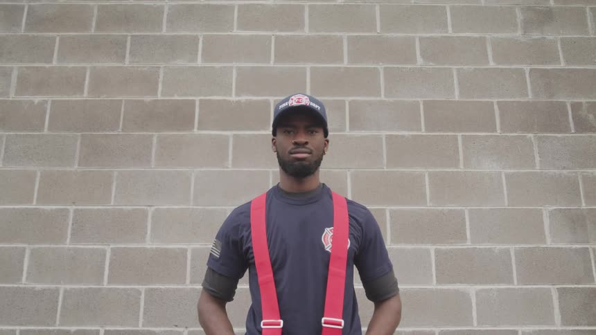 A young black man standing in front of a brick wall