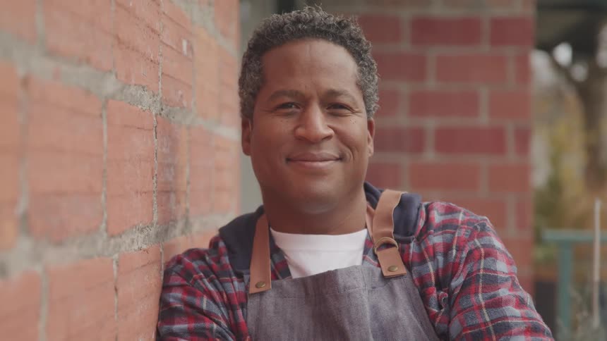 A man is standing outside of a building and smiling