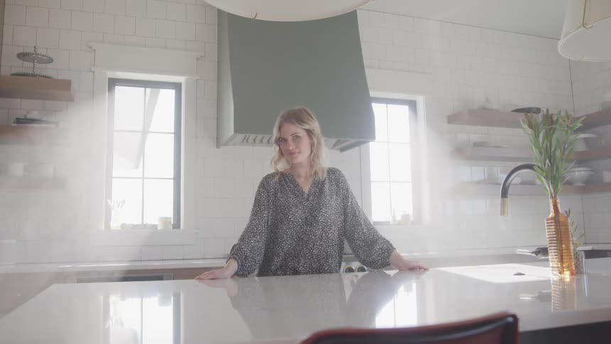 A woman stands in her kitchen by the island