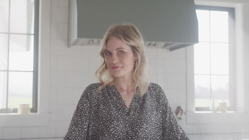 A woman is standing in a kitchen at midday
