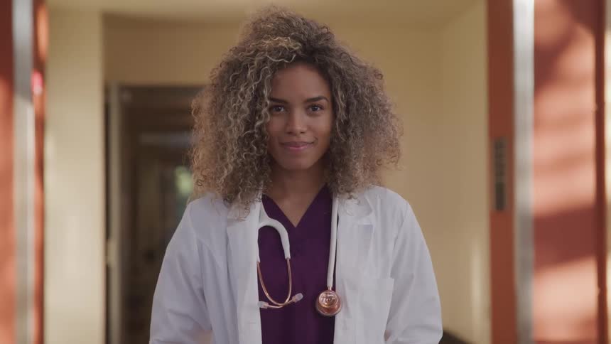A nurse stands in a hallway with a stethoscope around her neck