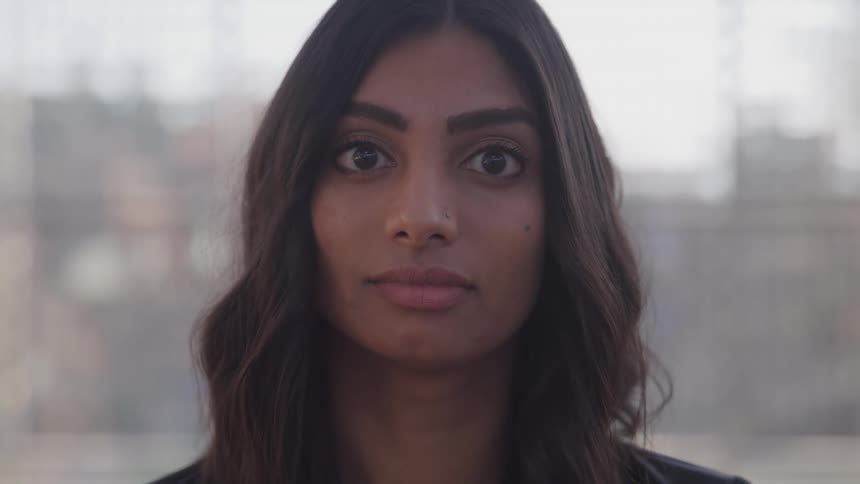 A woman turns toward the camera and stares while outdoors