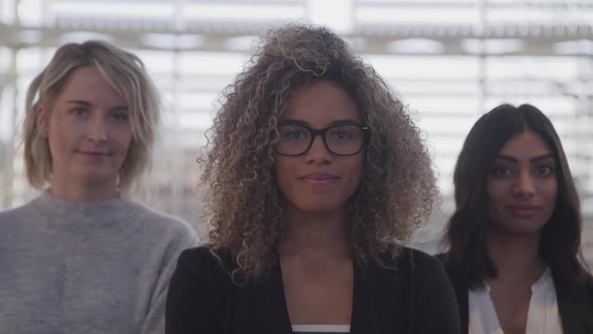 Three women are standing in a building and smiling