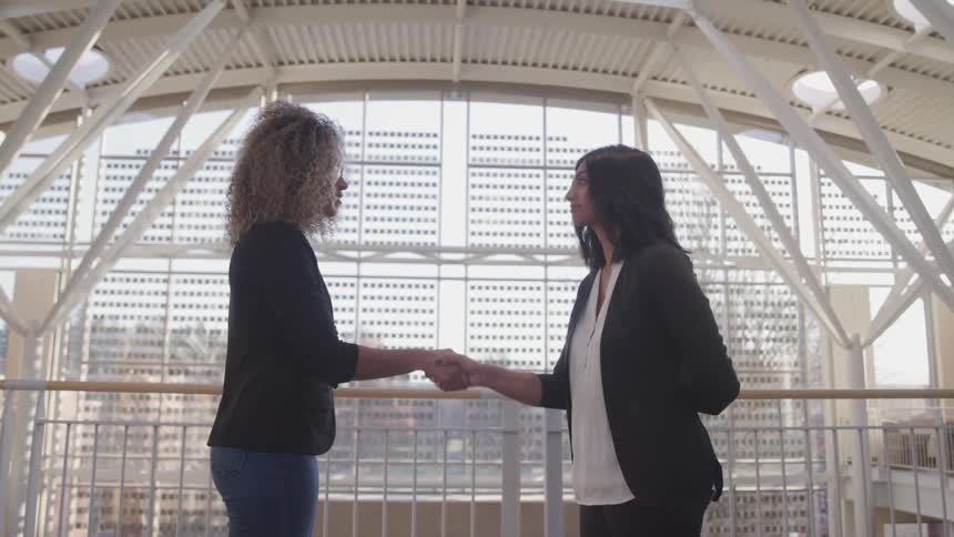 Two women are shaking hands in a building