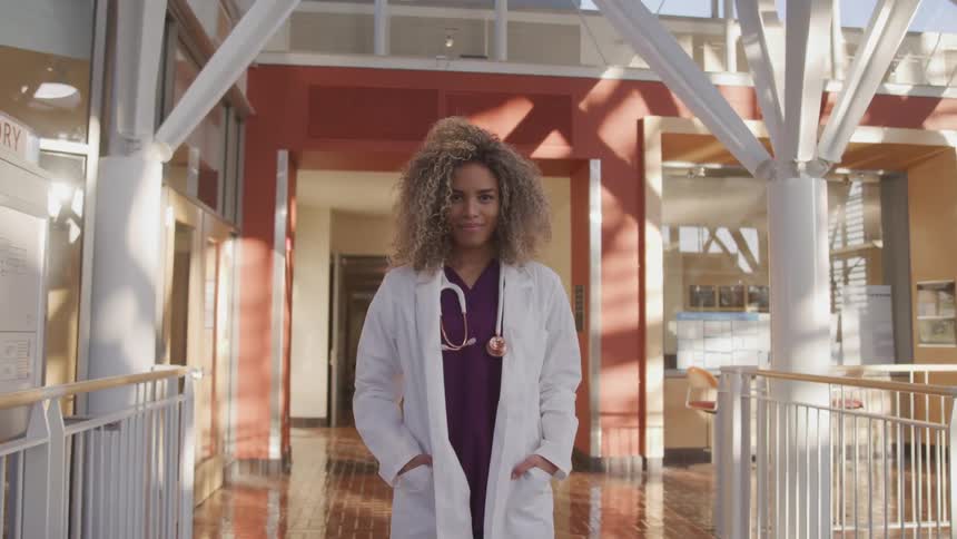 Doctor wearing a lab coat and sthetoscope looks up to the camera