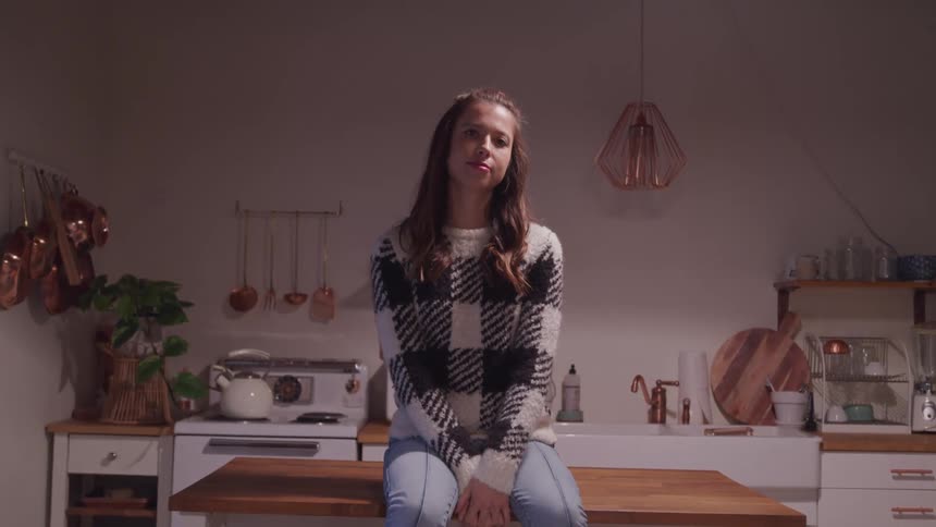 A teenage girl sits on a kitchen island