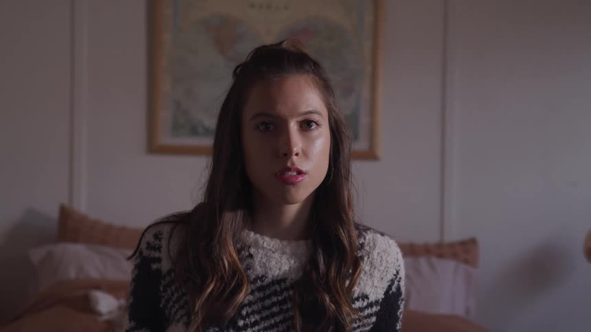 Woman sitting in a bed in the bedroom at home looks at the camera