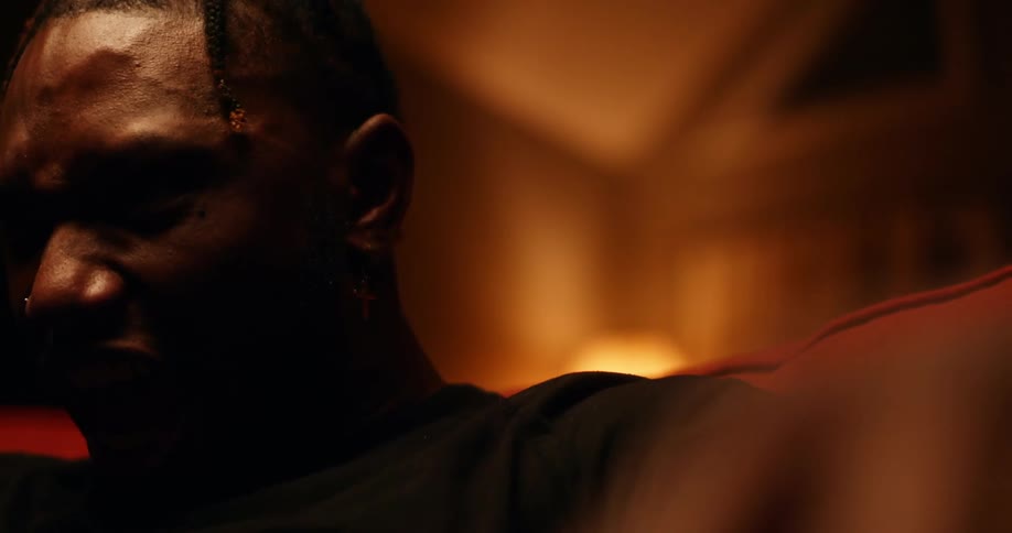 Man sitting in a couch in a dimly lit room screams in anger
