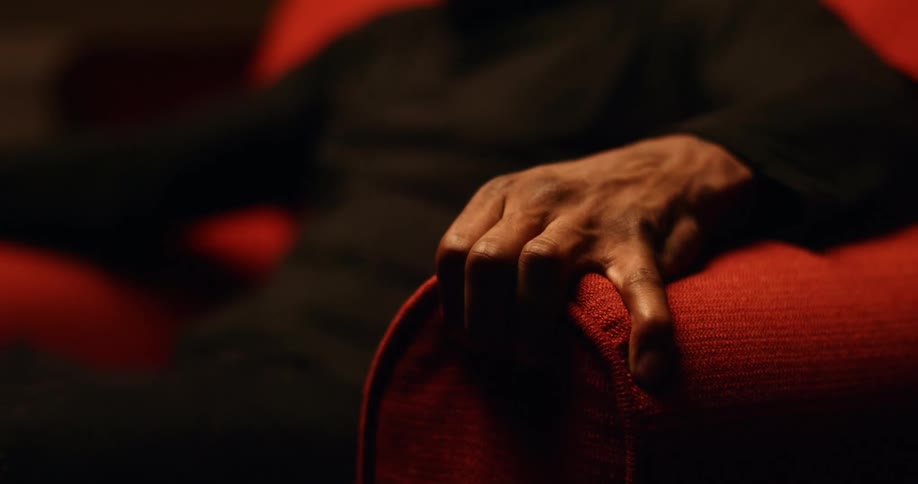 A man sitting in an armchair jumps and grips the chair