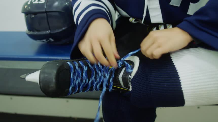 A child sitting on a bench putting on skates