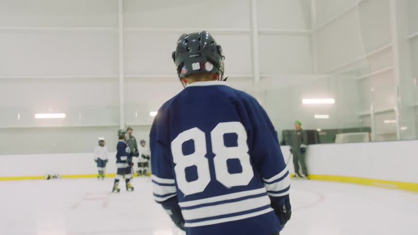 A person ice skates across a rink wearing hockey gear