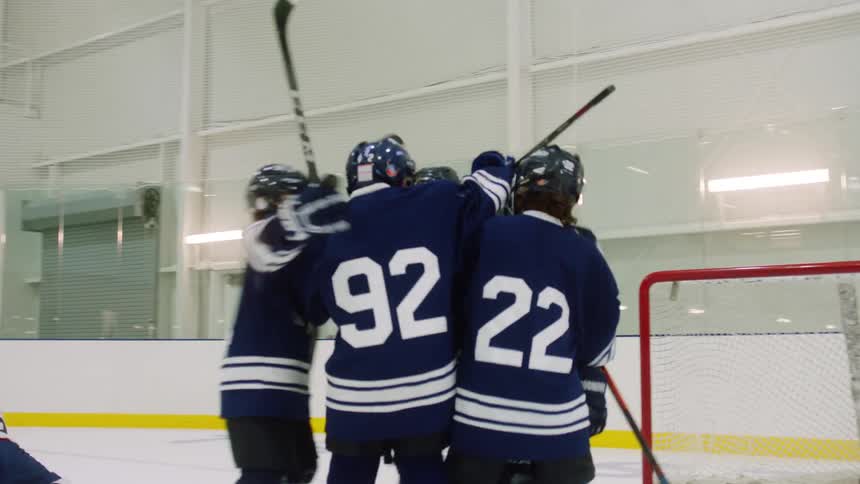 Team of boys playing hockey celebrate after scoring a goal