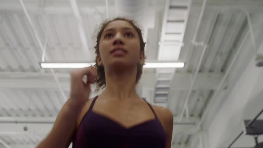 A young woman is running indoors while swinging her arms very quickly