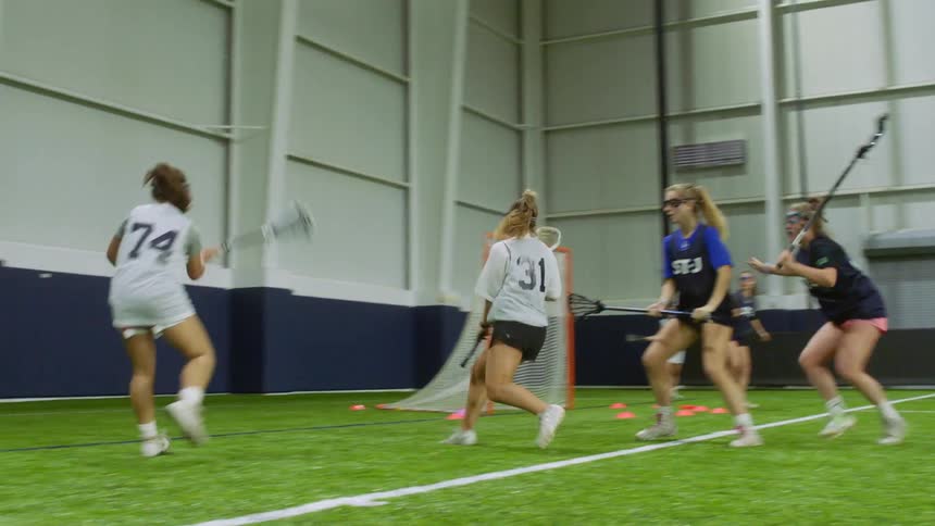 A group of teenage girls play indoor lacrosse