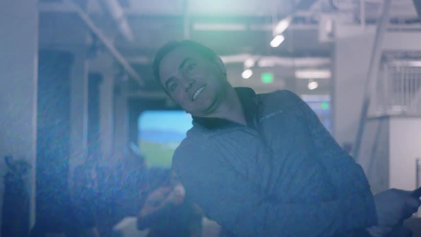 A man uses a golf club and swings with a virtual golf simulator